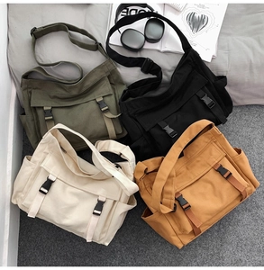 Détail de sacs bandoulière en toile en vert armée, noir, blanc cassé et couleur kaki