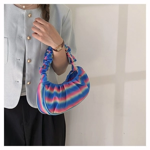 Close-up of pleated rainbow gradient dumpling bag worn on a model's shoulder for style