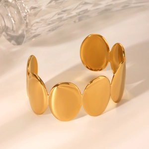 Détail de maillons ovales dorés superposés sur un bracelet jonc minimaliste en acier