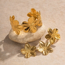 Detailed set of gold flower jewelry with textured petals and brushed finish on stone