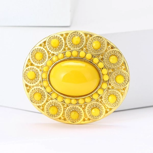 Macro shot of oval vintage gold brooch featuring a large yellow gemstone and intricate gems