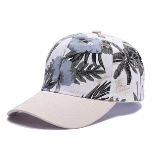 Floral print baseball cap with beige brim featuring tropical leaf and blue flower pattern