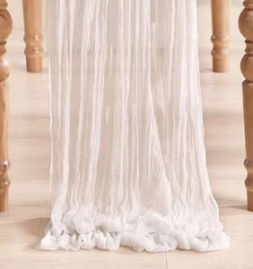 Detail of white cheesecloth table runner showing sheer texture and natural crinkle effect