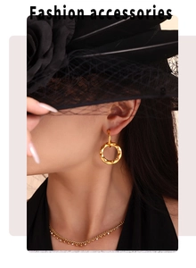 Close-up of elegant gold geometric hoop earrings and necklace on model with vintage hat
