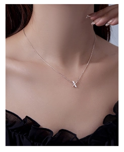 Detail of silver S925 necklace with criss-cross pendant and diamond inlay on female model