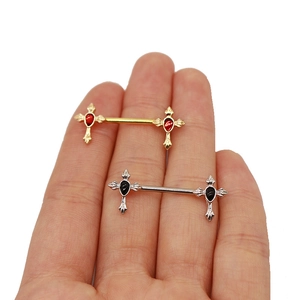 Detail shot of stainless steel cross nipple rings in gold and silver finish with studs