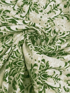 Close-up of vintage floral print fabric in green and cream with soft cotton texture