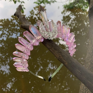 Macro shot of pink crystal crown with silver crescent moon on natural wood branch
