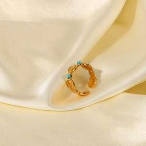 Detailed macro of a bohemian gold open ring with turquoise beads on soft silk fabric
