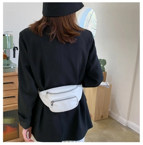 White PU leather waist bag shown worn across the back by a model in a cozy indoor setting