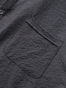 Detail of dark charcoal polo shirt featuring seersucker texture and chest pocket