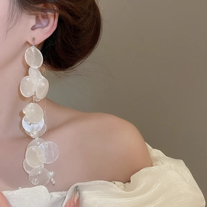 Macro detail of elegant long tassel earrings with pearlescent shells and white pearls