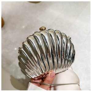 Silver shell-shaped clutch bag with golden knob and metallic chain close-up