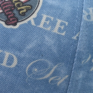 Detail of blue denim baseball cap featuring vintage embroidery and white printed letters