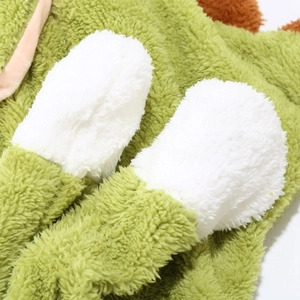 Detail of plush dinosaur hat featuring green faux fur texture and white circular patches