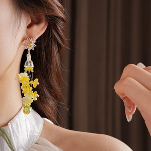 Gros plan de boucles d'oreilles à fleurs jaunes et pompons portées par un mannequin