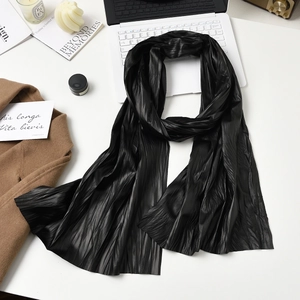 Elegant black pleated long scarf paired with a brown wool coat and modern workspace accessories