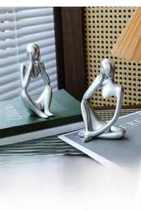 Close-up of minimalist silver thinker sculpture set with matte metallic resin finish