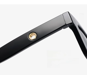 Detailed macro view of black sunglasses with curved temples and gold metal hinges