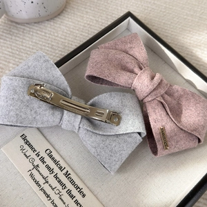Close-up of velvet bow hair clips with handmade metal tag on a decorative tray