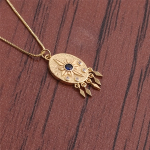 Detailed macro view of gold evil eye pendant with blue gem and diamond starburst tassels
