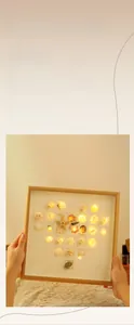 Detailed close-up of handmade seashell heart night light within a wooden picture frame