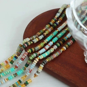 Handmade necklace with multi-color natural stone beads and gold accents on wood