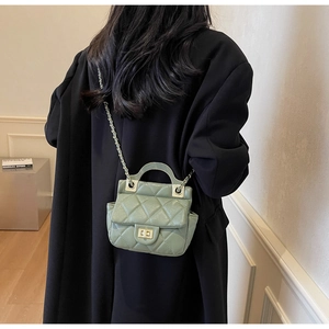 Detail of light green quilted crossbody bag with metal chain strap on black coat
