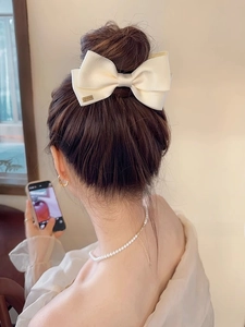 Close-up of a large cream satin bow hair claw with a gold 'LOVEDAYS' metal plate
