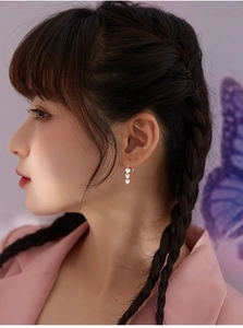 Close-up of triple heart-shaped drop earrings in silver finish on a model