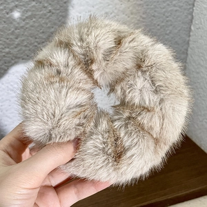 Close-up of plush faux fur hair scrunchie in brown and beige animal print texture