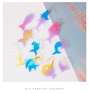 Detailed view of DIY resin ocean earrings featuring glitter shark and dolphin shapes