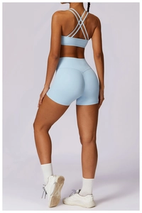 Rear view of light blue cross-back sports bra and high-waist yoga shorts set