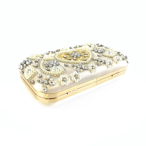 Detail of luxury champagne gold evening bag with pearls, rhinestones, and heart pattern