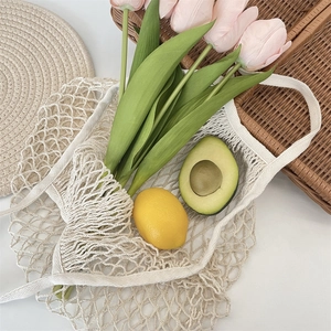 Detail of beige woven mesh bag featuring cotton rope material with fresh flowers and fruits