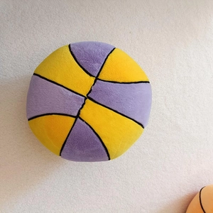 Close-up of yellow and purple basketball plush pillow with soft texture on white rug