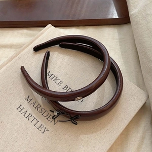 Dark brown leather headbands set with gold metal detail on beige book background