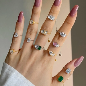 Model hands wearing adjustable gold and silver chain rings with colorful zircon stones