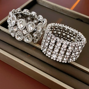 Gros plan de larges bracelets argentés avec strass blancs dans un écrin en velours marron
