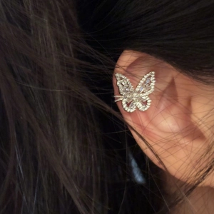 Close-up detail of an elegant silver butterfly ear cuff with sparkling zircons worn on ear
