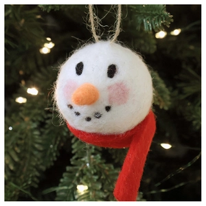 Close-up of handmade wool felt snowman ornament hanging on a festive Christmas tree