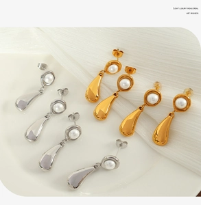 Detail of gold and silver pearl waterdrop earrings on white silk fabric background