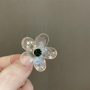 Primer plano de pinza de pelo de flor transparente con una piedra verde central