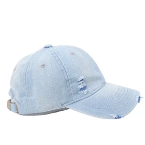 Detailed view of distressed light blue denim baseball cap with vintage frayed holes