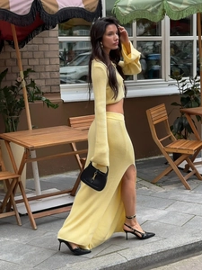 Detail of pale yellow knitted long sleeve top and side slit maxi skirt on street