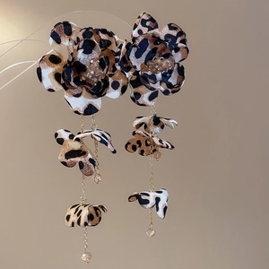 Detail of leopard print fabric flower earrings with long gold tassels and rhinestones