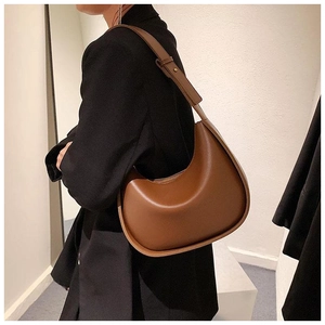 Sac bandoulière demi-lune en cuir marron porté épaule avec sangle réglable par le mannequin