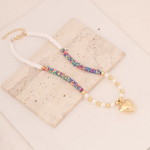 Detail of bohemian polymer clay necklace with gold heart pendant and pearls