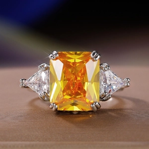 Detalle macro de un anillo de tres piedras con centro amarillo de talla radiante y plata
