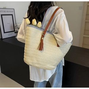 Detail of woven straw tote bag with brown tassel charm and striped lining for summer